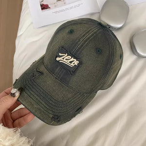 Distressed cotton baseball cap in dark gray with a "zero" patch and frayed details.