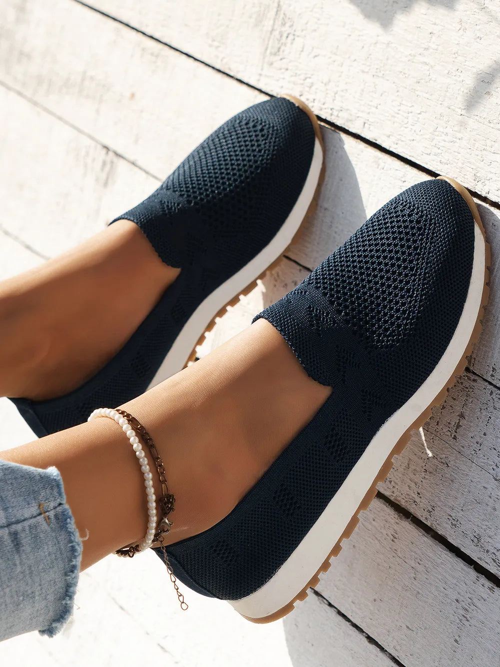 Dark navy breathable knit slip-on sneakers with white soles and a gum outsole.