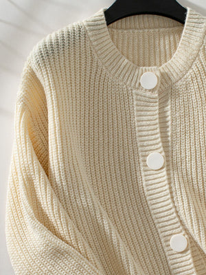 Cream knit button-up cardigan with round neckline and ribbed texture.