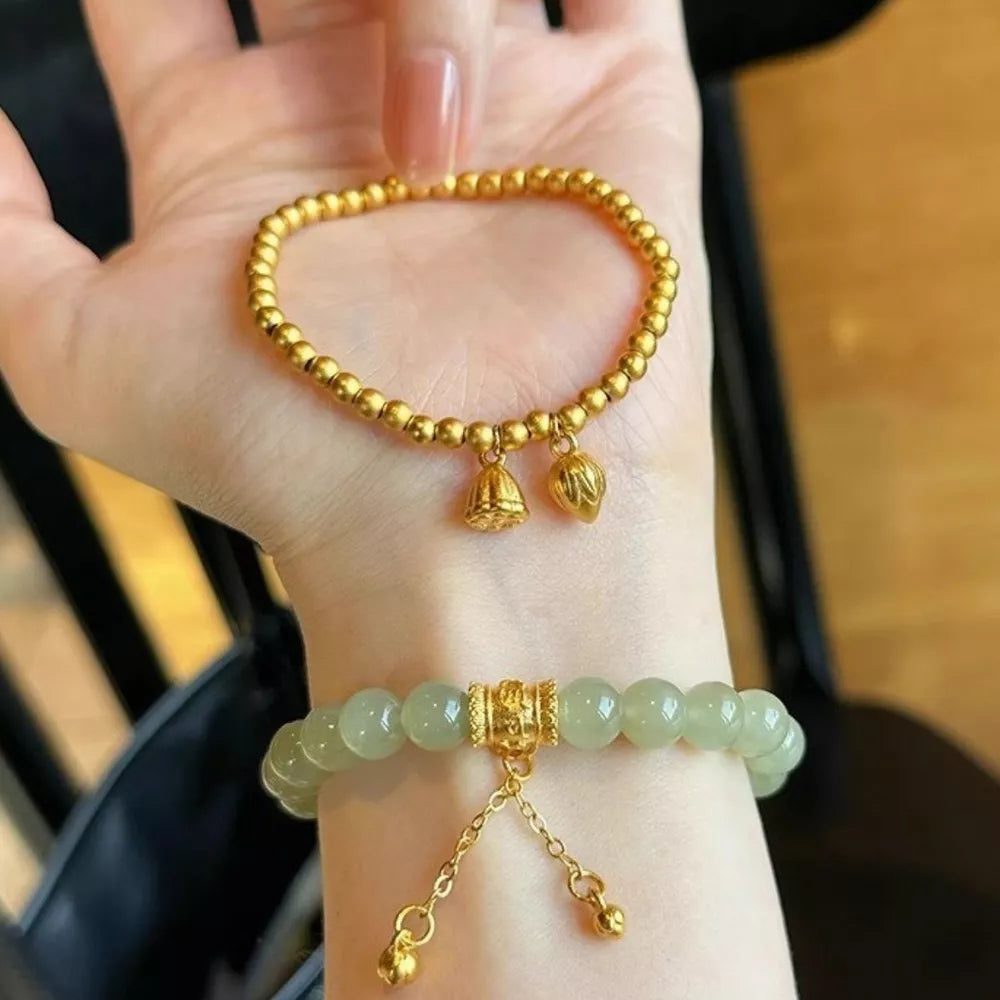 Delicate 18k gold-plated bead bracelet with bell and lotus charms.