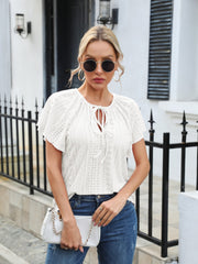 White perforated tie-neck flutter sleeve blouse with eyelet detail.