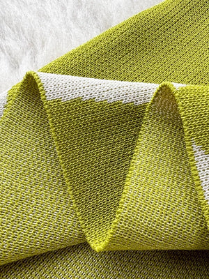 Green wavy knit midi dress with spaghetti straps, close-up detail.