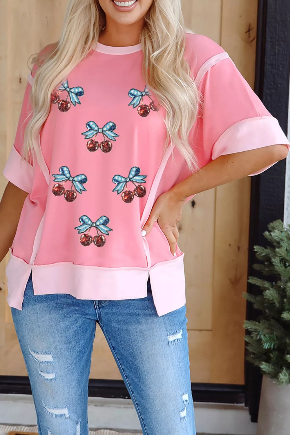 Pink t-shirt with sequin cherry and bow graphic, contrast trim, and side slits.