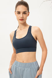 Mesh-inset performance sports bra in deep teal with scoop neck and racerback straps.
