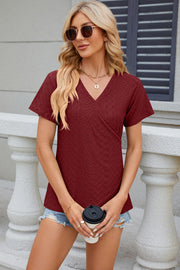 Burgundy eyelet wrap v-neck top with short sleeves and a textured pattern.