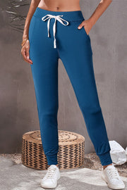 Dark blue slim-fit joggers with white drawstring and cuffed ankles.