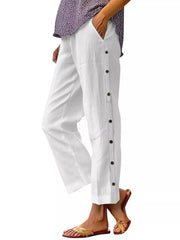 White relaxed fit pants with decorative buttons down the side and pockets.