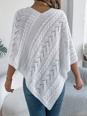 White cable knit poncho with chevron detail and V-neck, styled with jeans.
