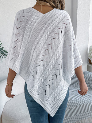 White cable knit poncho with chevron detail and V-neck, styled with jeans.