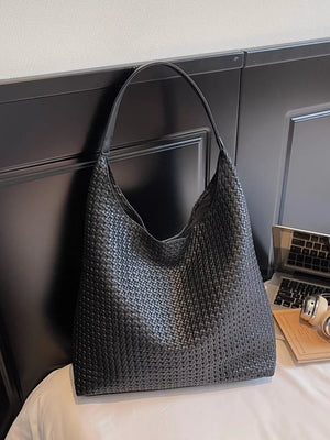 Black woven straw texture tote bag with a slouchy trapezoid shape and single strap.