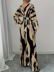 Abstract print wide leg jumpsuit with V-neck, belted waist, and flared sleeves.