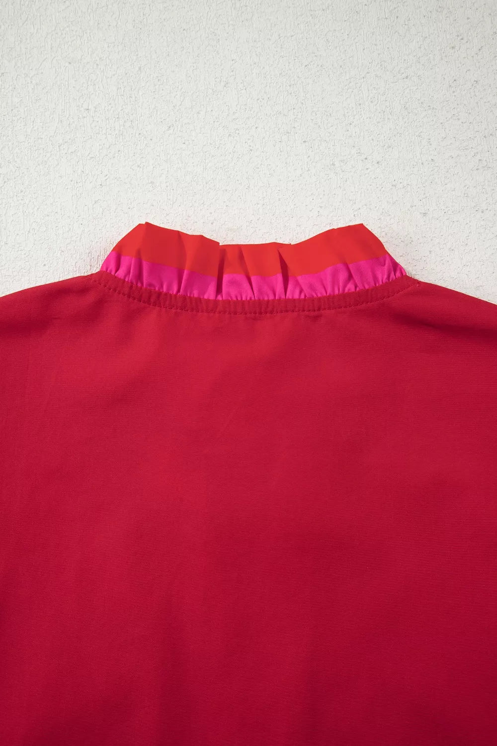 Ruffled maternity blouse in red with pink and red striped ruffle collar detail.