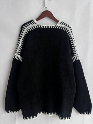 Black oversized knit cardigan with contrast white stitching detail on neckline and hem