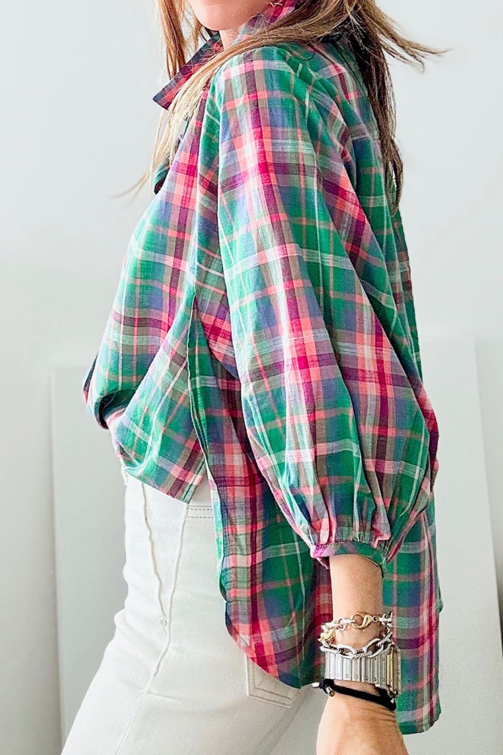 Voluminous plaid blouse with gathered sleeves and a relaxed fit, styled with white pants.