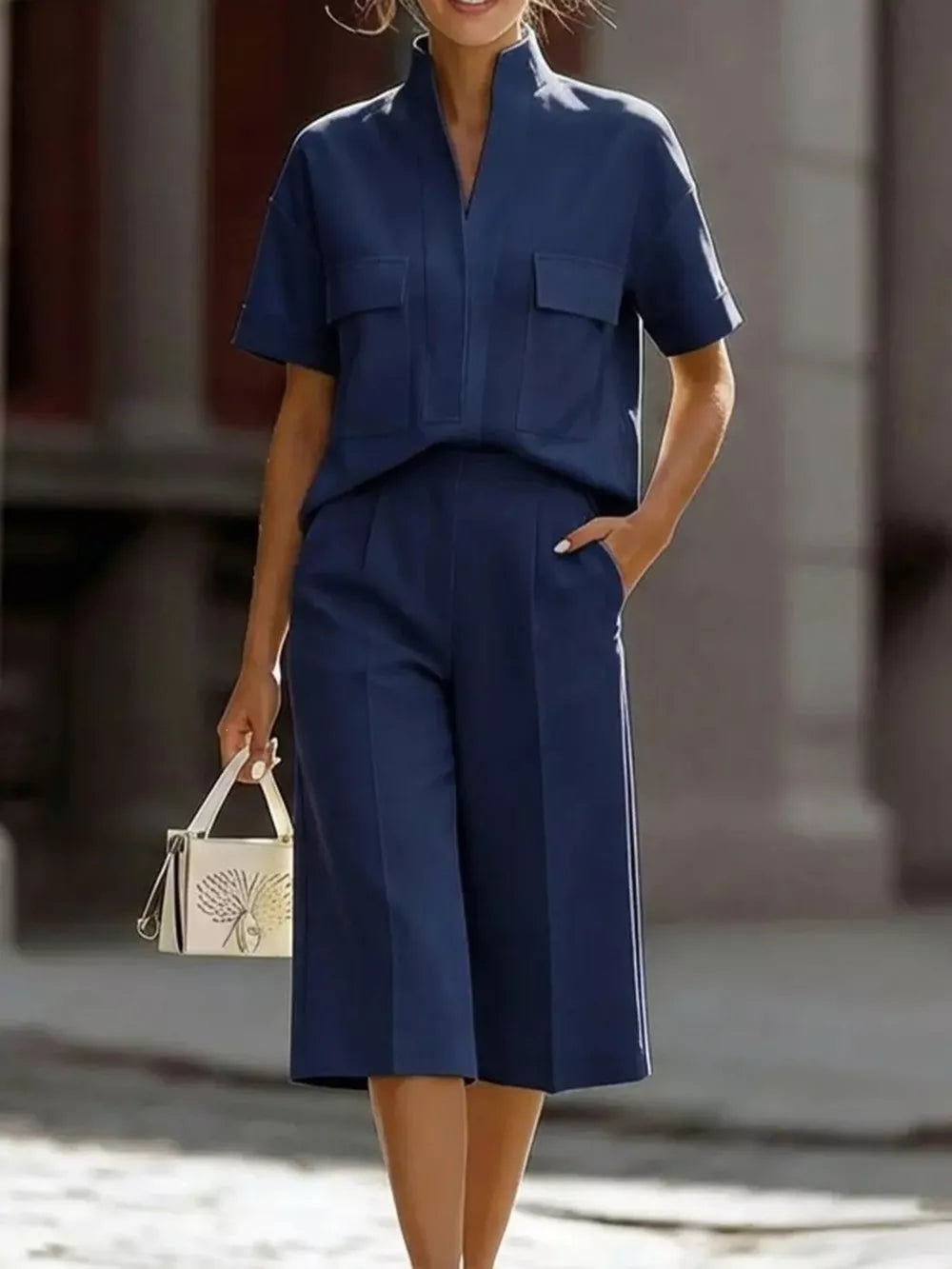 Navy two-piece set with short sleeves, mock neck, and pocketed top, paired with wide-leg cropped pants.