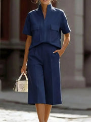 Navy two-piece set with short sleeves, mock neck, and pocketed top, paired with wide-leg cropped pants.