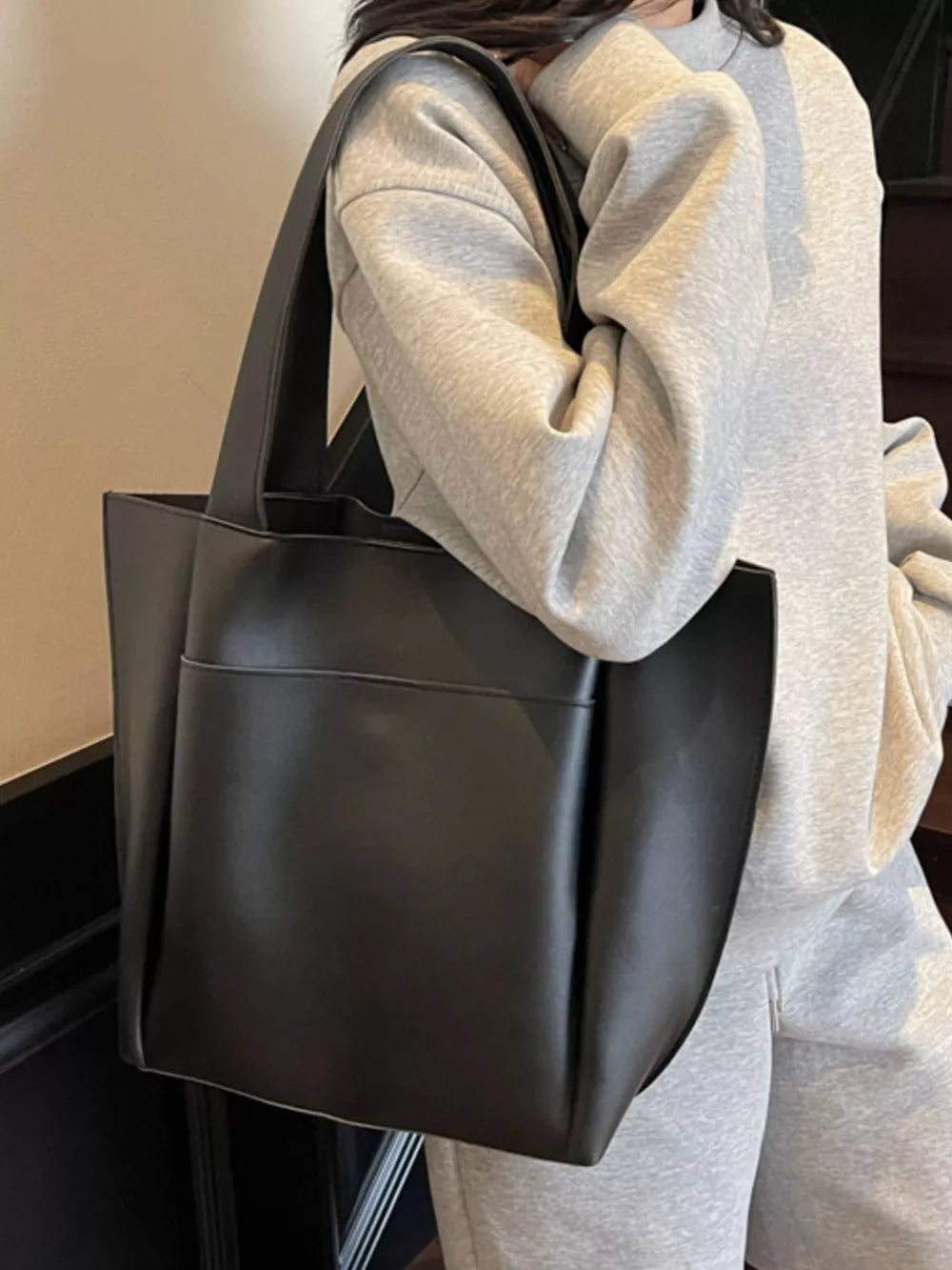 Black pu leather tote bag with front pocket and shoulder strap.
