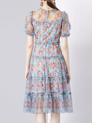 Ruffled floral dress with sheer sleeves and tiered skirt.