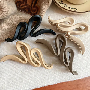 Sculptural hair claws in black, tan, dust storm, and coffee brown with serpentine design.