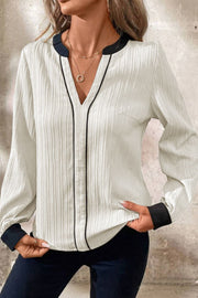 White textured V-neck blouse with black trim and cuffs.