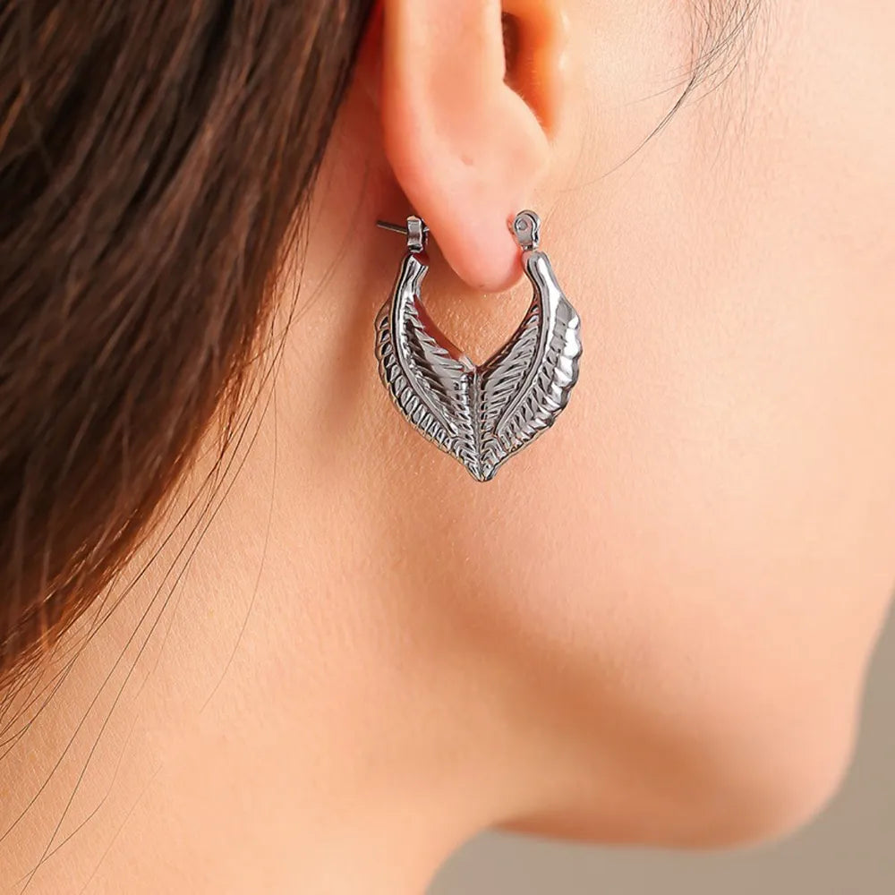Silver textured leaf hoop earrings with a detailed feather design.