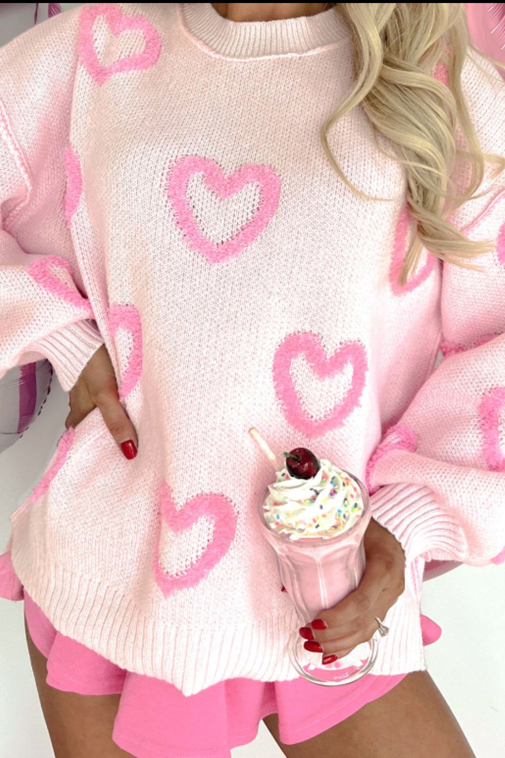 Pink knit sweater with allover heart appliqué and balloon sleeves.