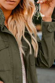 Army green utility jacket with multiple pockets and buttoned cuffs, worn casually.