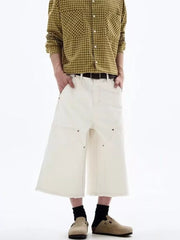 Men's white cotton wide-leg cropped cargo pants with raw hem and contrast stitching.