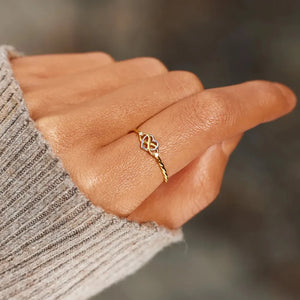 Gold intertwined heart and infinity ring on a finger, 18K gold and sterling silver.