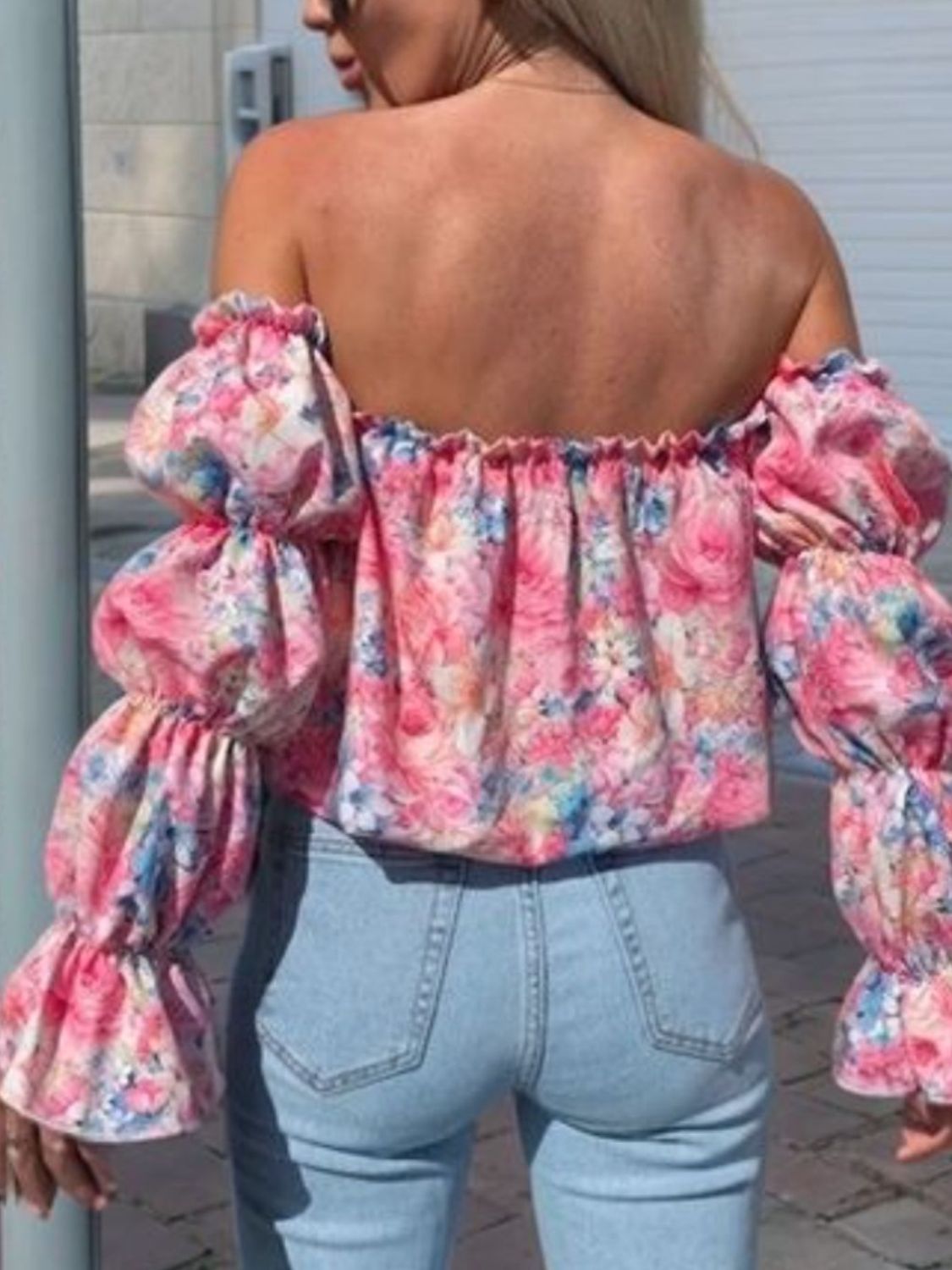 Off-the-shoulder blouse with ruffle sleeves and a floral print in pink and blue.