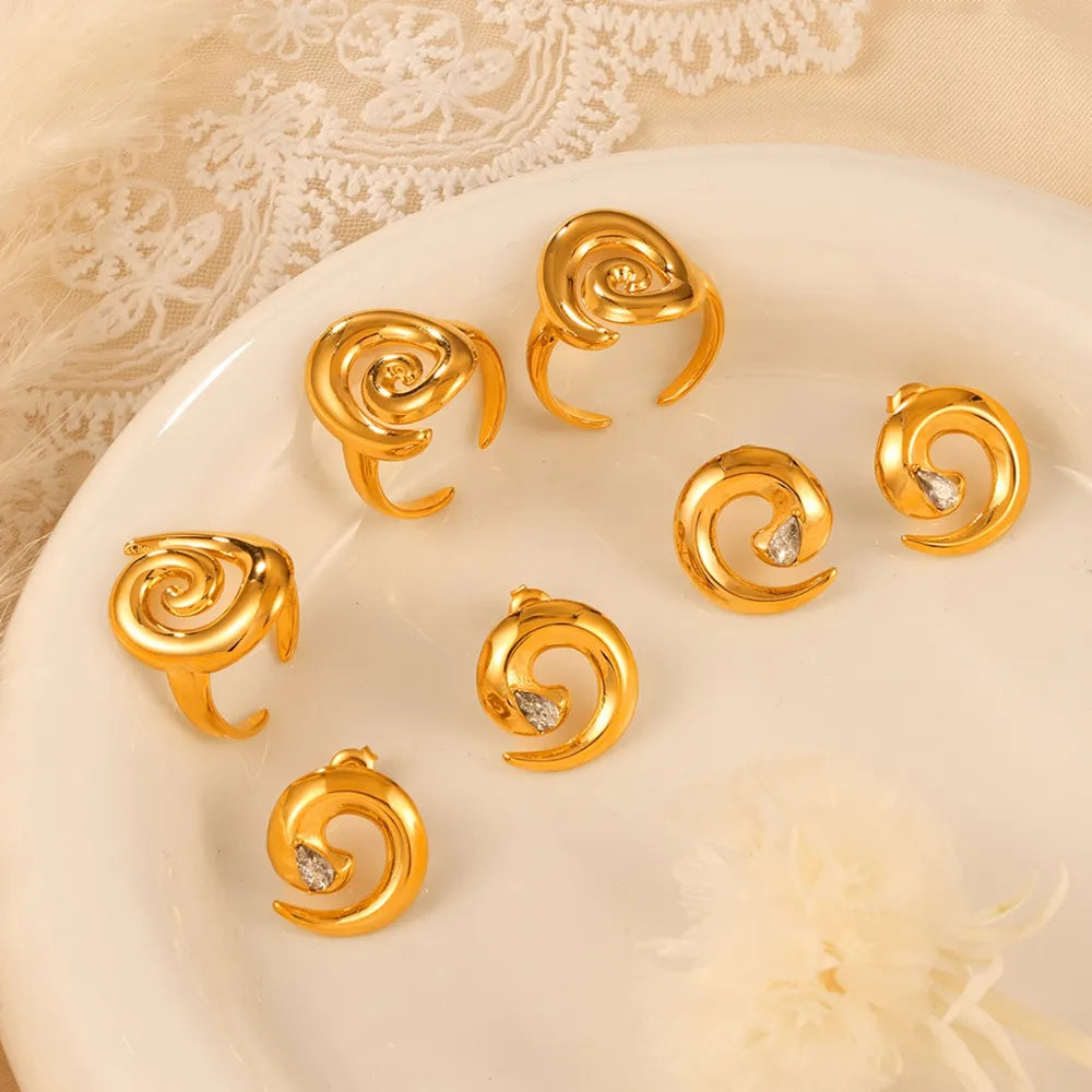 Gold sculptural swirl rings and stud earrings with clear stones.