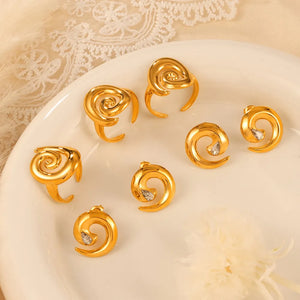 Gold sculptural swirl rings and stud earrings with clear stones.