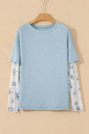 Light blue textured maternity overshirt with sheer floral print sleeves.
