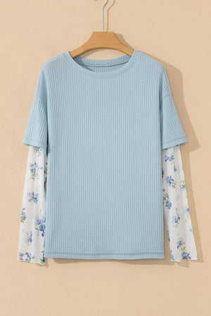 Light blue textured maternity overshirt with sheer floral print sleeves.