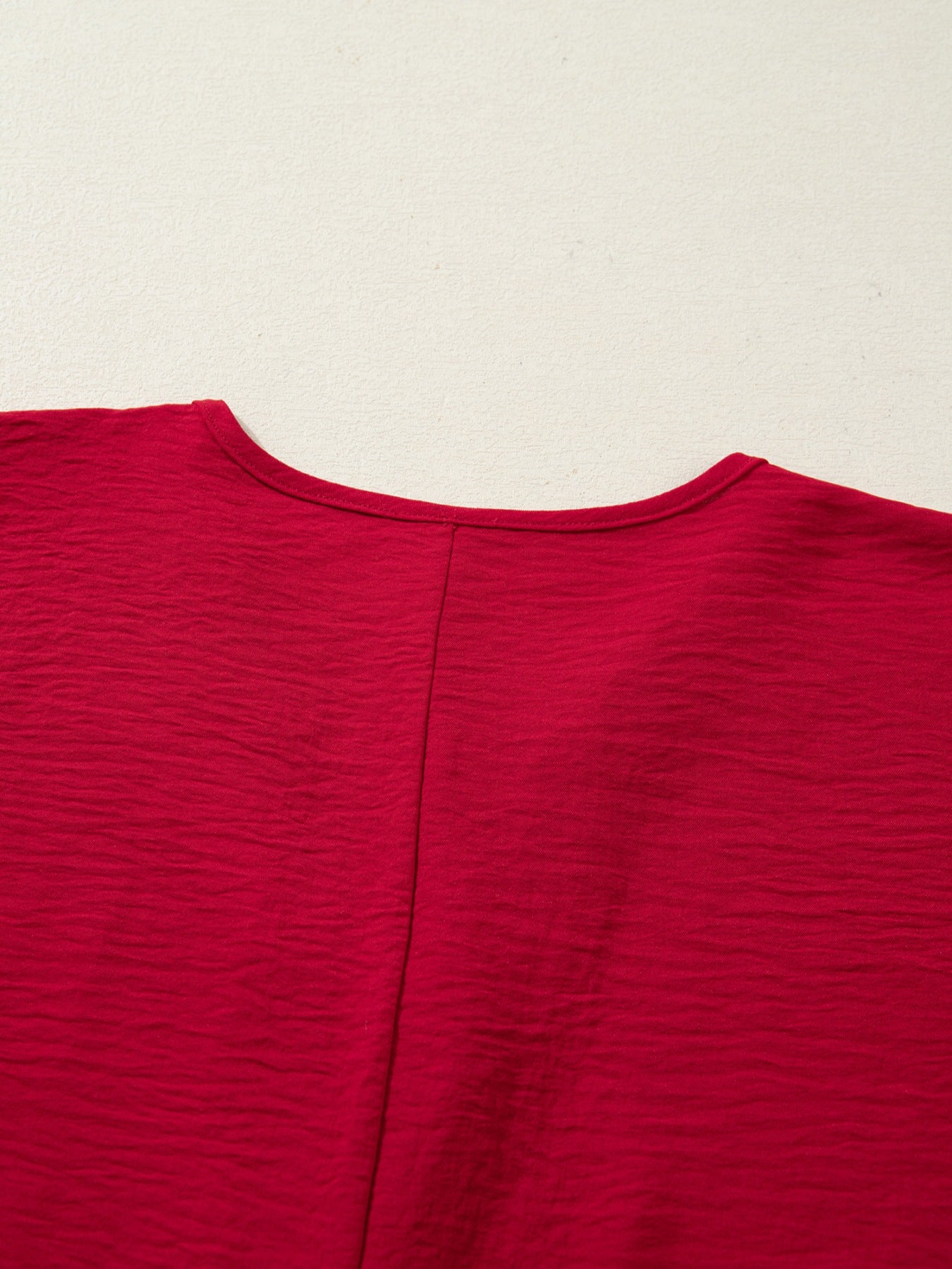 Braided V-neck half sleeve blouse in deep red with textured fabric and a center seam.