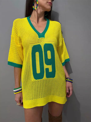 Yellow openwork knit tunic sweater with green trim and large green number 09 graphic.