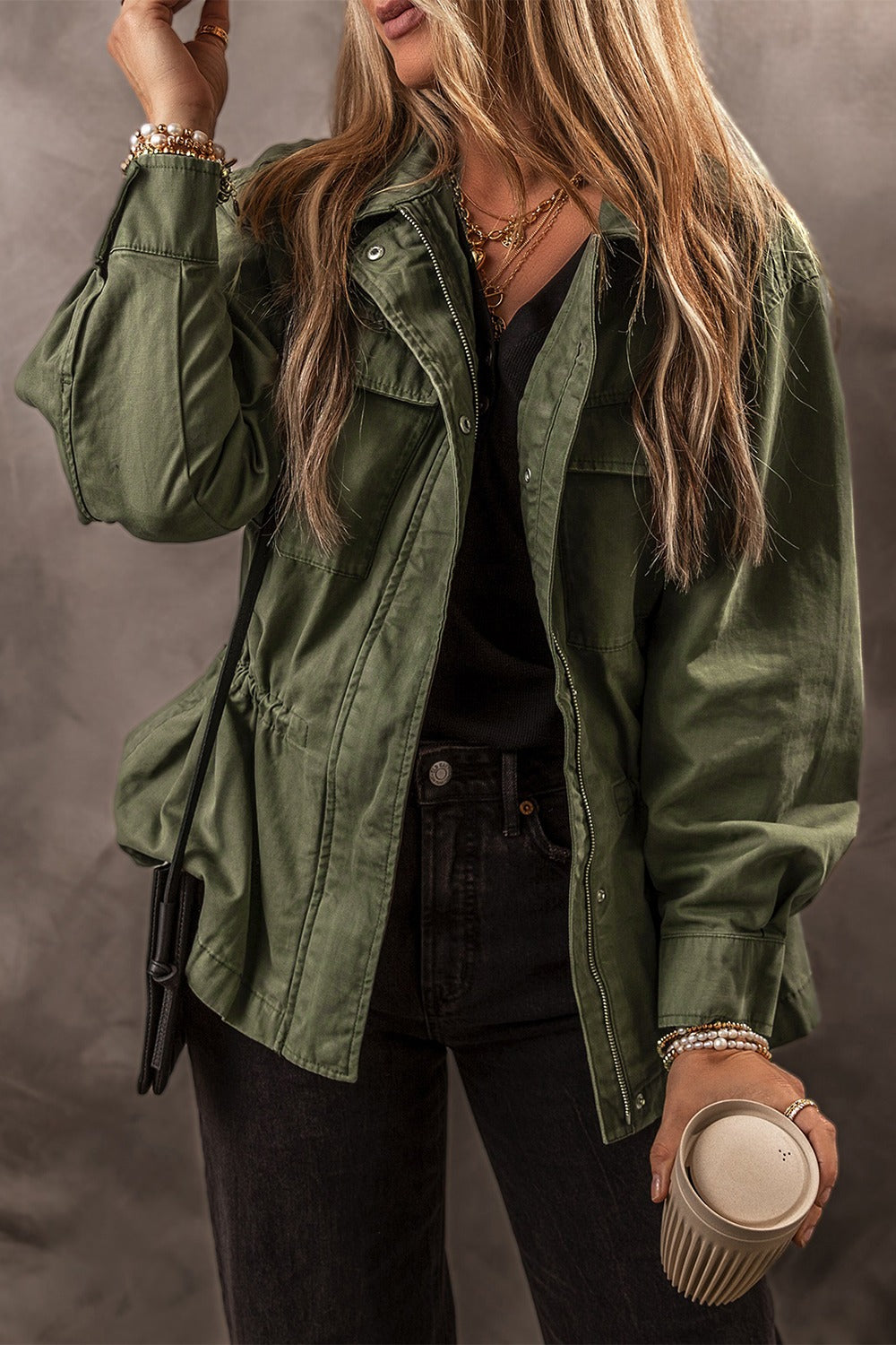 Army green military-inspired jacket with drawstring waist and chest pockets.