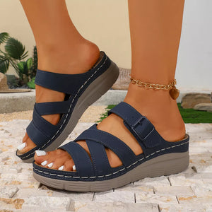 Blue multi-strap wedge sandals with criss-cross straps and adjustable buckle detail.