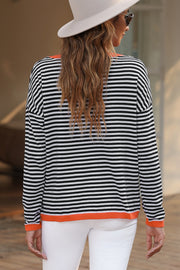 Striped crewneck sweater with contrast orange trim and long sleeves.