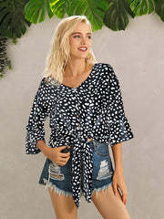 Black spotted knot-front blouse with flared sleeves and button detail.