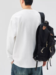 White casual oversized long-sleeve sweatshirt with crew neck, styled with jeans and a backpack.
