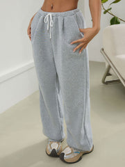 Light gray relaxed sweatpants with pleat-front detail and drawstring waist.