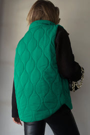 Green quilted stand-collar gilet with wave pattern, worn over a black sweater.