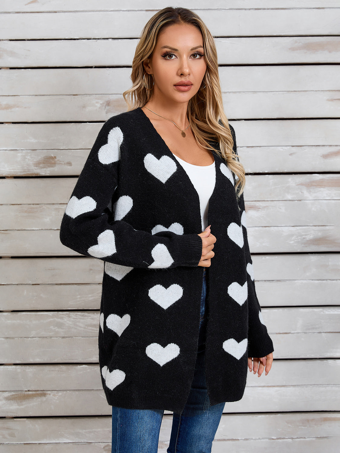 Black acrylic cardigan with white intarsia hearts, open front, long sleeves.