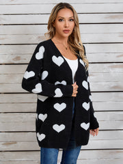 Black acrylic cardigan with white intarsia hearts, open front, long sleeves.