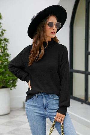 Black textured turtleneck sweater with long sleeves and a relaxed fit.