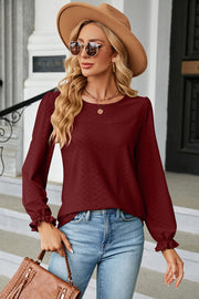 Burgundy textured puff sleeve blouse with ruffled cuffs and crew neck.