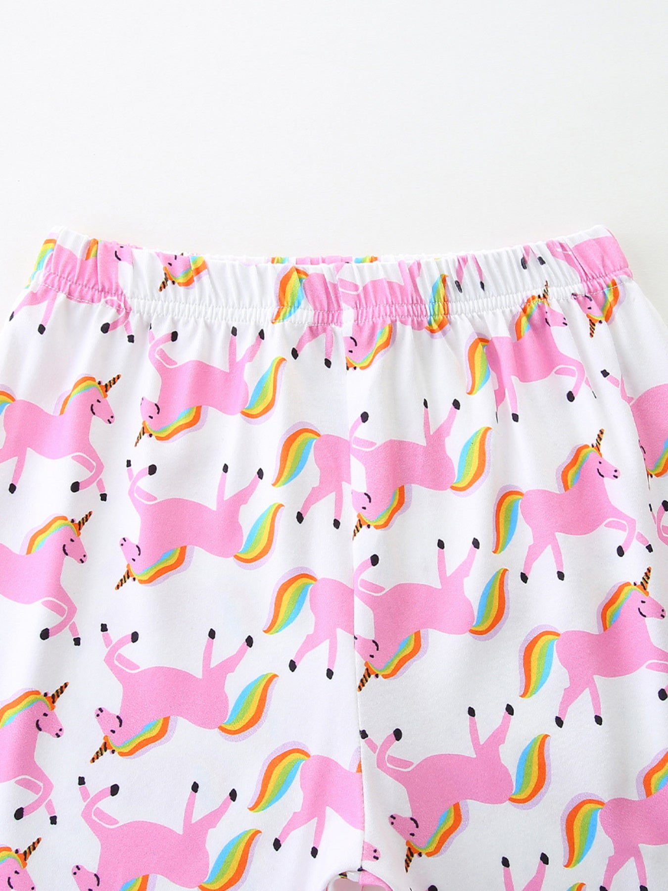 White girls' undershirt with pink unicorns and rainbow tails print.