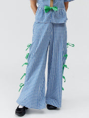 Blue gingham wide-leg trousers with green bow details down the sides.