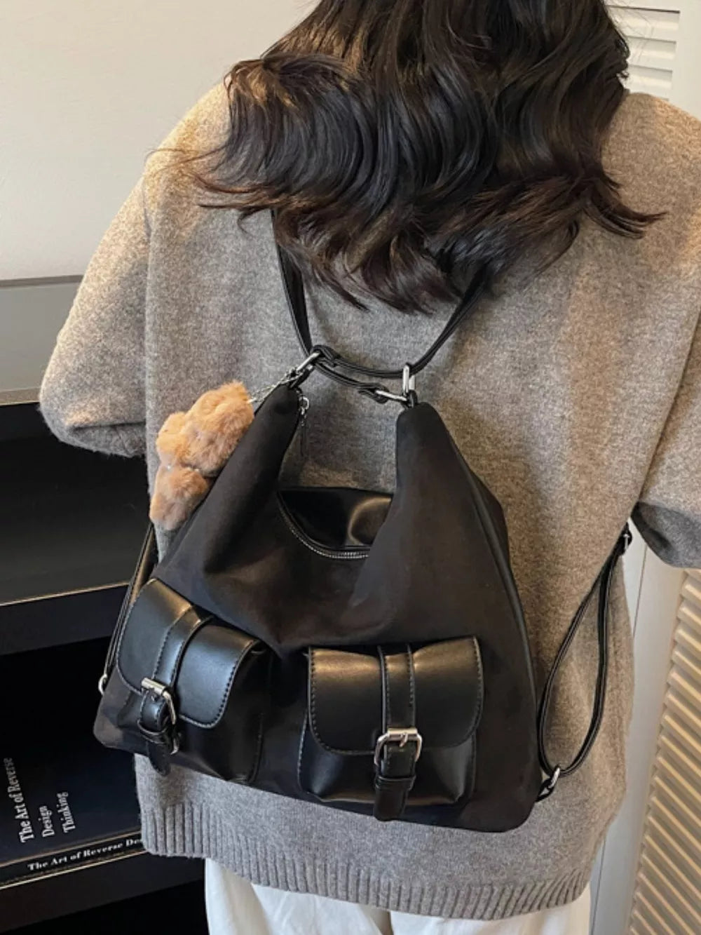Black suede half-moon bag with double front buckle pockets and fluffy charm